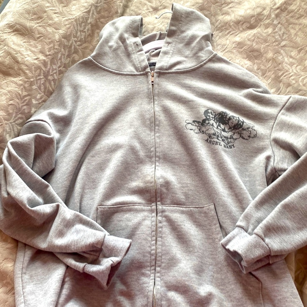 Cozy cotton zip up hoodie. Graphic angel design placed on a grey fabric.